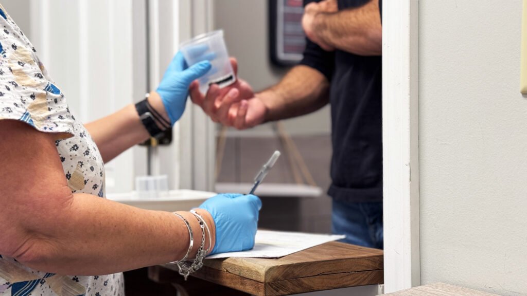 Collector hands specimen cup to donor at clinic